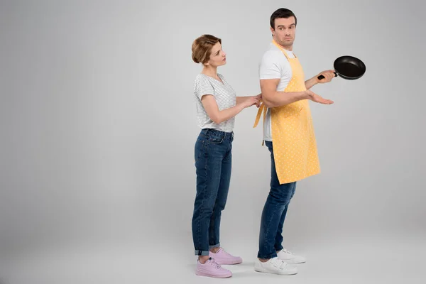 Wife and husband in apron with frying pan, feminism concept, isolated on grey — Stock Photo