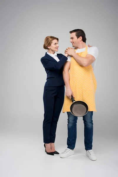 Businesswoman and male householder standing together with frying pan, feminism concept, isolated on grey — Stock Photo