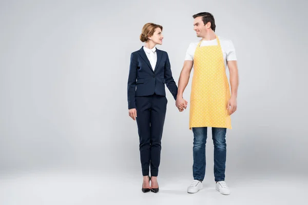 Businesswoman in suit and male householder holding hands, feminism concept, isolated on grey — Stock Photo