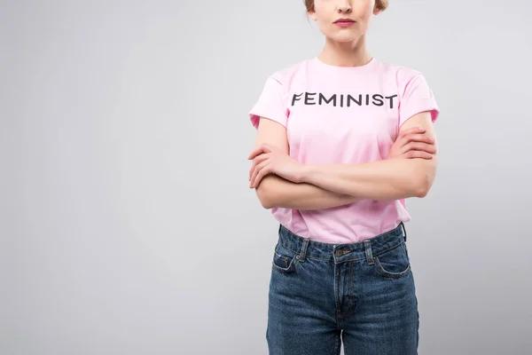 Vue recadrée de la femme en t-shirt féministe rose posant avec les bras croisés, isolé sur gris — Photo de stock