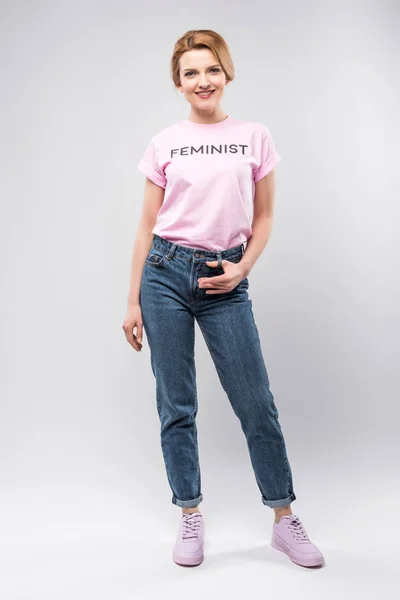 Bella donna sorridente in t-shirt femminista rosa, isolata sul grigio — Foto stock