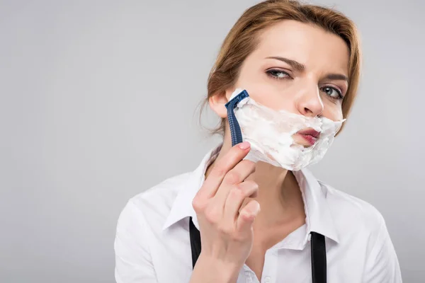 Mujer de negocios afeitándose la cara, aislada en gris, concepto feminista - foto de stock