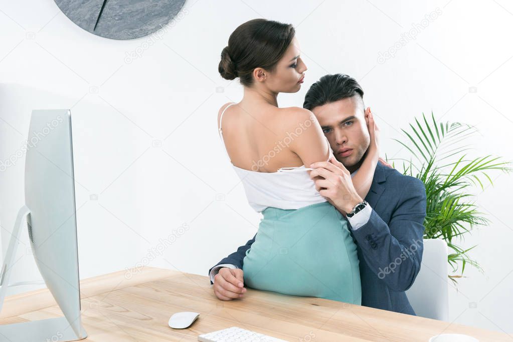 businesspeople hugging in foreplay at workplace