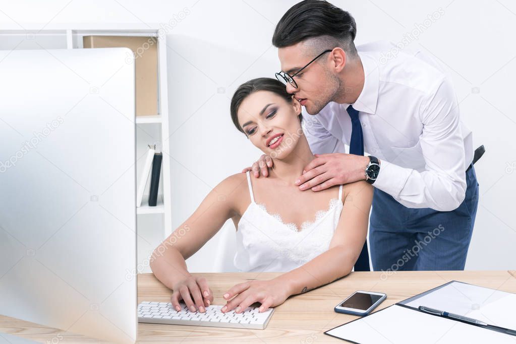 businessman whispering to beautiful colleague at office