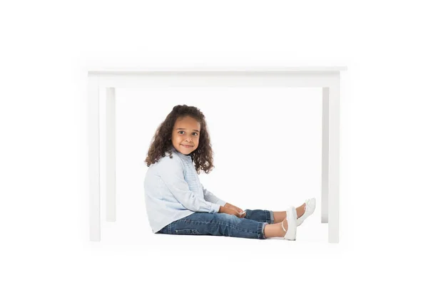 African american girl sitting under table — Stock Photo, Image
