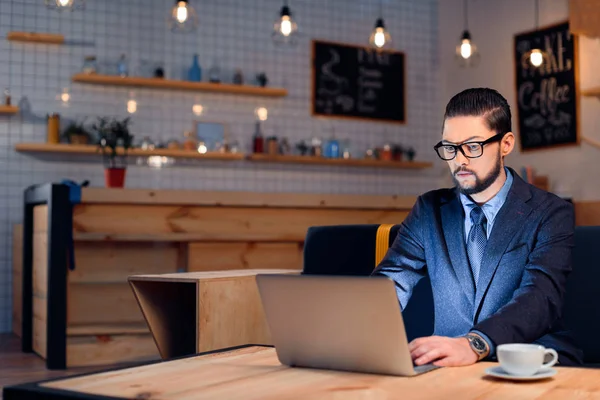 Biznesmen korzysta z laptopa w kawiarni — Zdjęcie stockowe