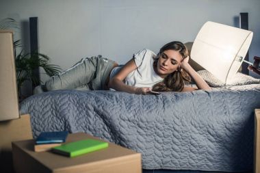 Evde akıllı telefon kullanan bir kadın.