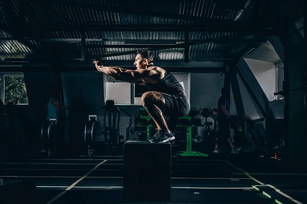 Sportman doen squats op kubus — Stockfoto