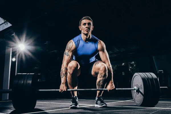Athletic sportsman lifting barbell — Stock Photo, Image
