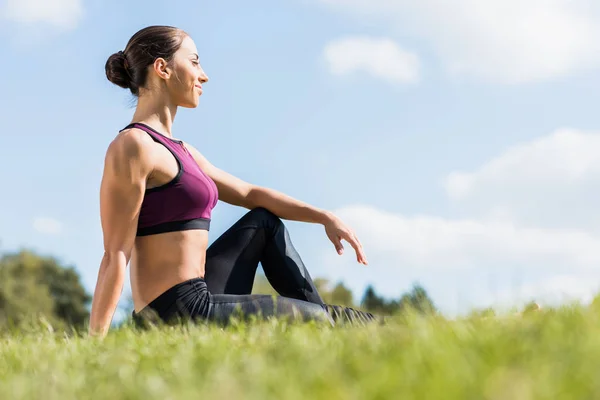 Sportlerin sitzt auf Gras — Stockfoto