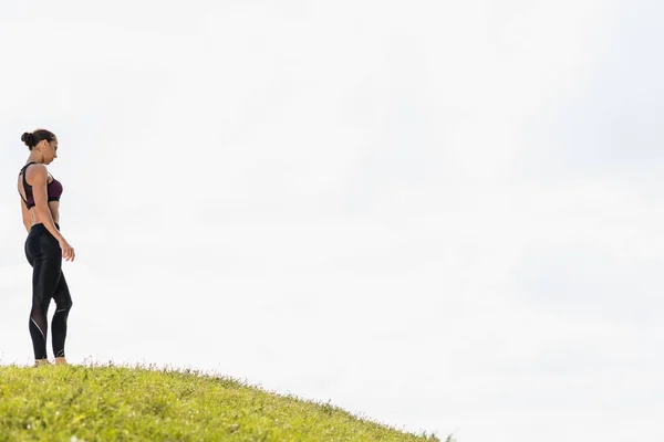 Fit woman standing on grass hill — Stock Photo, Image