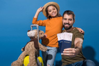 father and daughter with passports and tickets going on vacation on blue clipart
