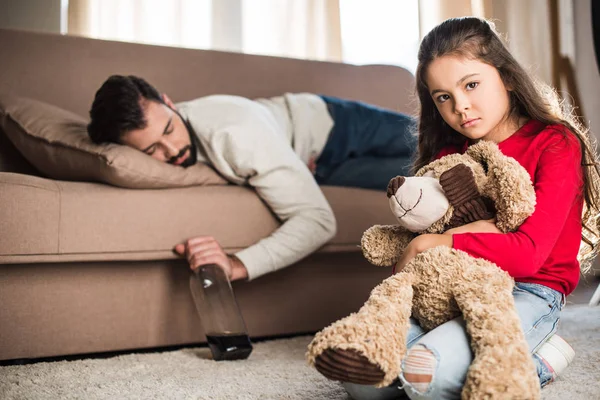 Sad Daughter Sitting Teddy Bear While Drunk Father Sleeping Sofa — Stock Photo, Image