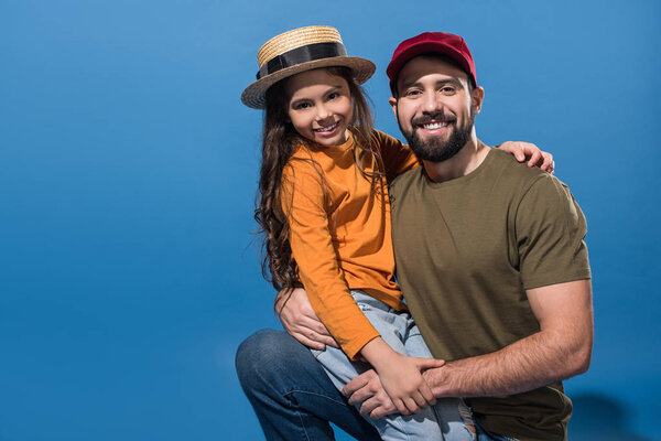 daughter sitting on father knee on blue 