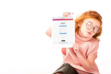 Kızıl saçlı çocuk oturan ve üzerinde beyaz izole tablet yüklü instagram sayfa gösterme