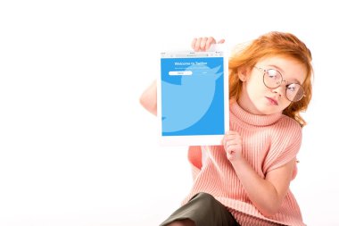 Kızıl saçlı çocuk oturan ve üzerinde beyaz izole tablet dolu heyecan sayfa gösterme
