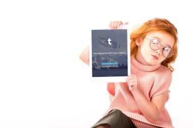 Kızıl saçlı çocuk oturan ve üzerinde beyaz izole tablet yüklü tumblr sayfa gösterme