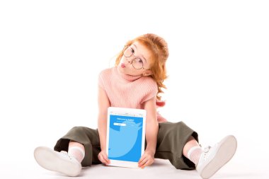 oturma ve beyaz tablet ile dolu heyecan sayfa tutan Kızıl saçlı çocuk