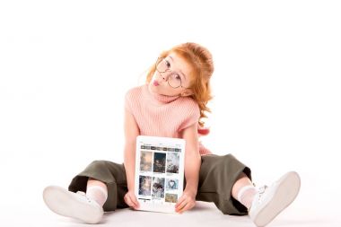 oturma ve beyaz tablet ile yüklenen pinterest sayfa tutan Kızıl saçlı çocuk