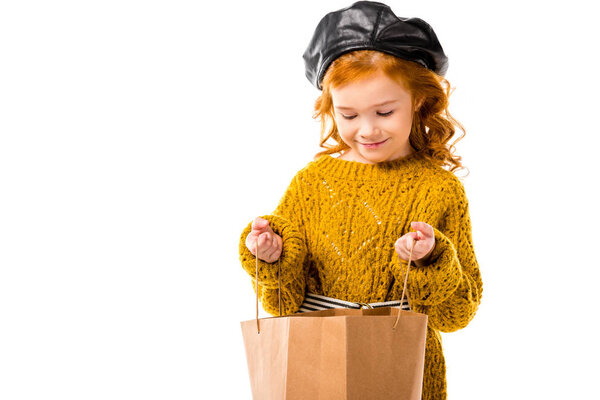 happy redhead child looking into shopping bag isolated on white 