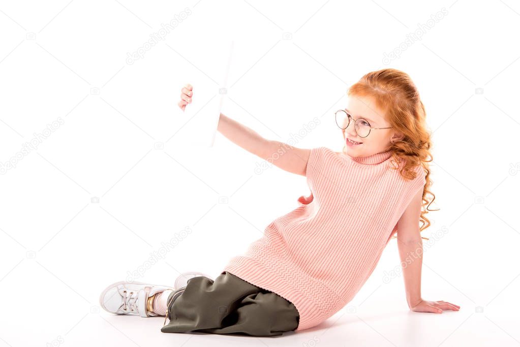 kid with ginger hair taking selfie with tablet on white