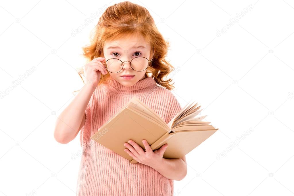 red hair kid looking above glasses and holding book isolated on white