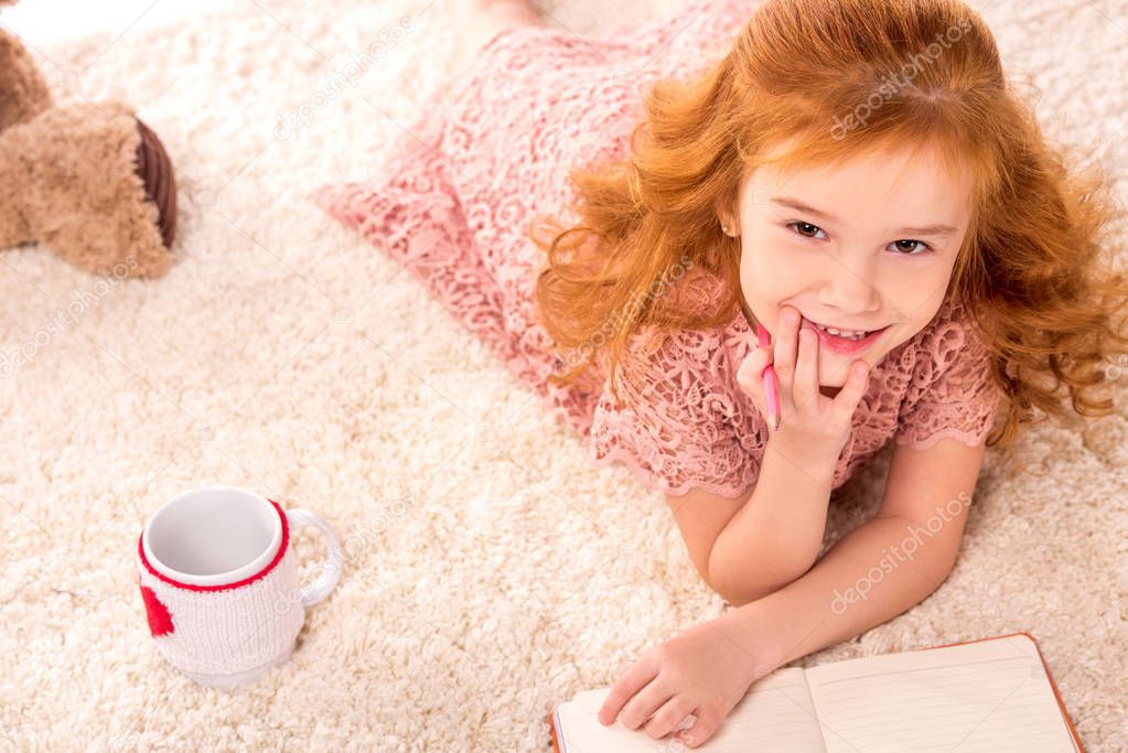 overhead view of dreamy redhead kid lying on fluffy carpet