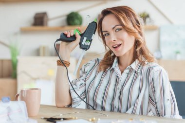 happy young woman with glue gun in handmade workshop clipart