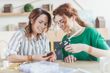 young women making accessory with glue gun clipart