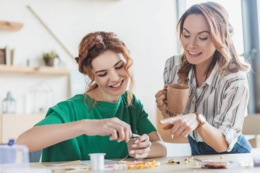 happy young women making accessories with linesman pliers in workshop clipart