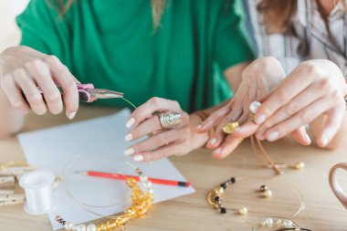 cropped shot of women making accessories of beads clipart
