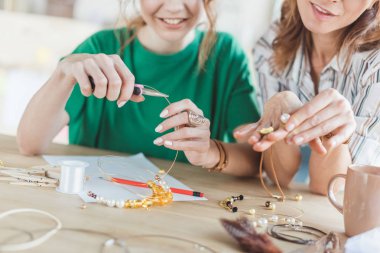cropped shot of women making accessories with linesman pliers in workshop clipart