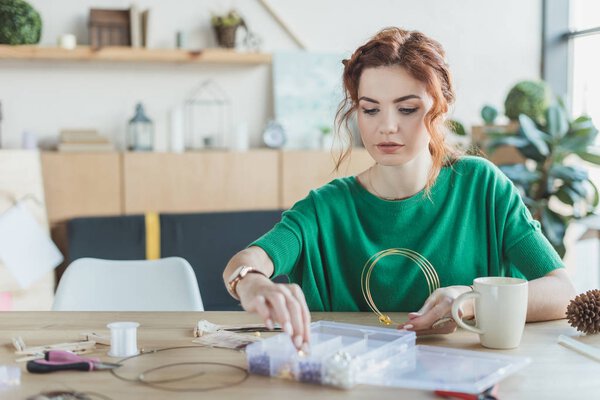 young woman making necklaces in handmade workshop