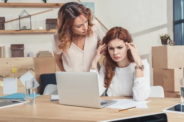 Stressed young manageress looking at laptop while boss talking to her — Stock Image Stressed Young Manageress Looking Laptop While Boss Talking Her Royalty Free Stock Images
