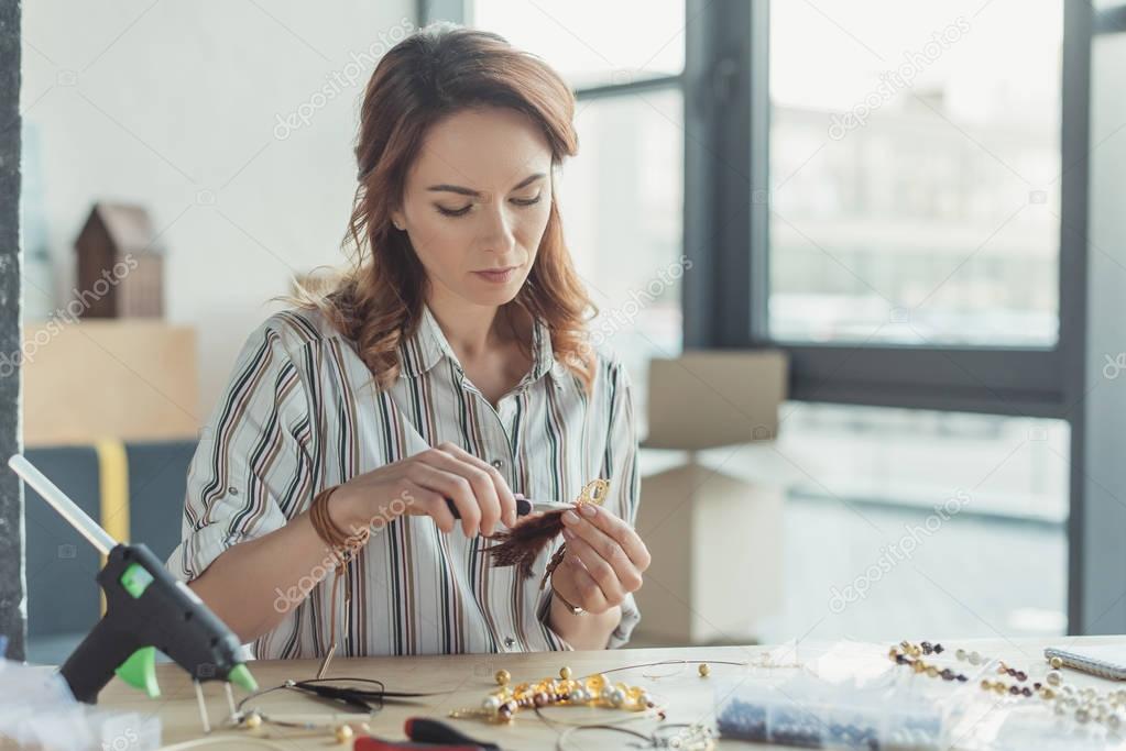 concentrated young woman making accessories in workshop