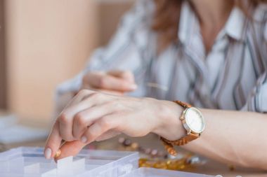 cropped shot of young woman making accessory of beads clipart