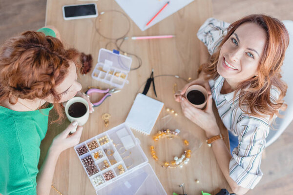 high angle view of happy young women drinking coffee in handmade accessories workshop