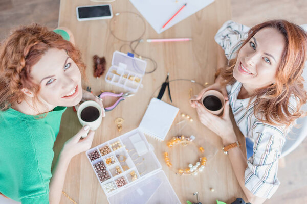 high angle view of young women drinking coffee in handmade accessories workshop