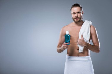 banyo havlusu diş durulama şişeyle elinde tutan, gri izole omuz üzerinde olan adam 