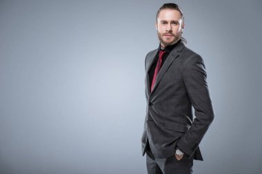 İşadamı resmi kıyafetli elleri cebinde, gri izole kameraya bakıyor 