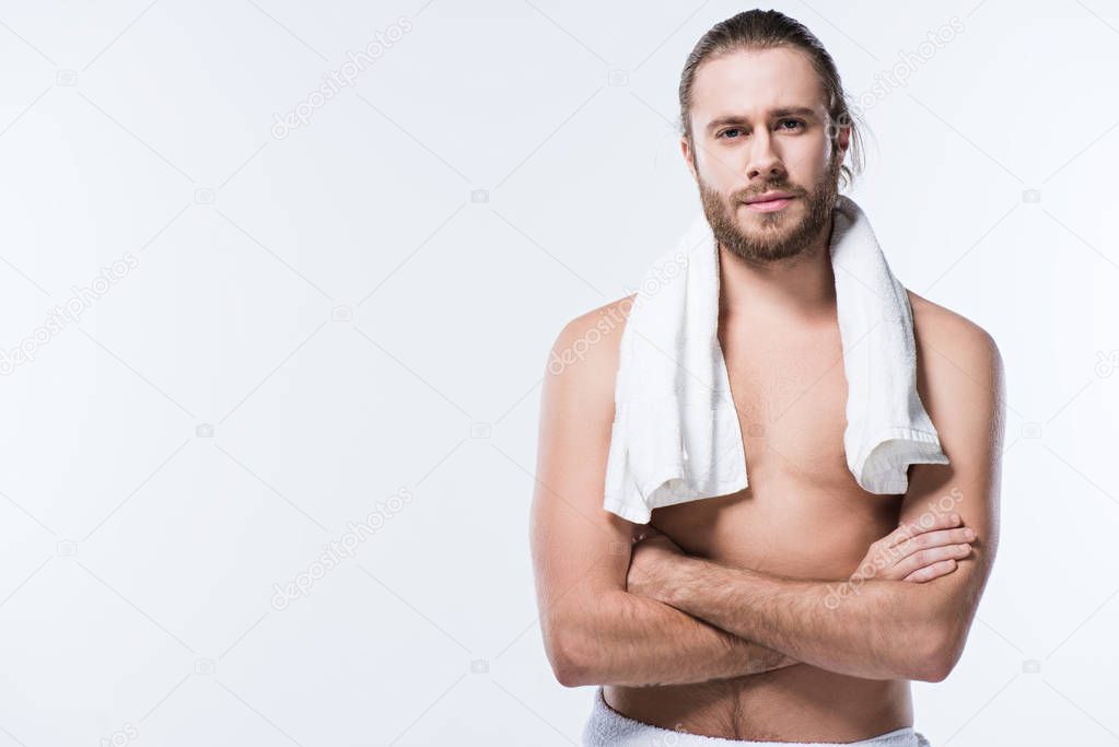 Cheerful caucasian man with bath towel around his neck looking at camera with arms crossed, isolated on white