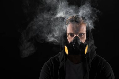 Siyah başlıklı duman bulutları tarafından çevrili koruyucu Filtre maskesi giyen adam