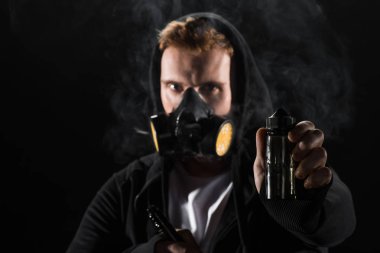 Man wearing protective filter mask smoking electronic cigarette showing E-liquid  clipart