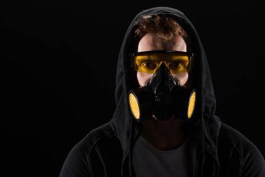 Man in black hood wearing protective glasses and filter mask isolated on black clipart