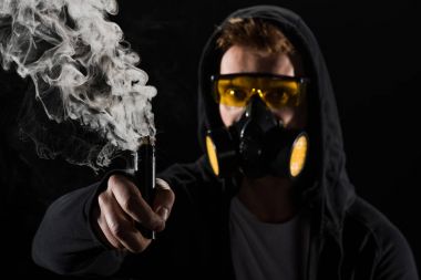 Man wearing protective filter mask activating electronic cigarette clipart