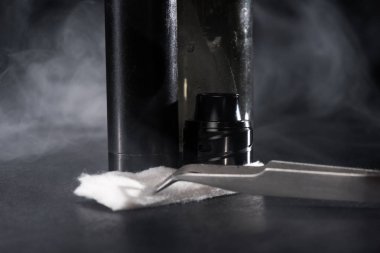 Elektronik sigara ve sıvı duman koyu arka plan üzerinde bulutlar ile