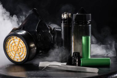 Elektronik sigara ve koruyucu Filtre maskesi ile koyu arka plan üzerinde duman bulutları