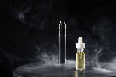 Electronic cigarette and liquid with clouds of smoke on dark background clipart