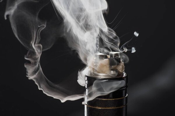 Activating electronic cigarette with clouds of smoke on dark background