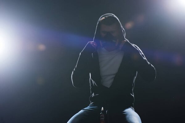 Man wearing protective filter mask smoking electronic cigarette against backlit